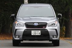 the front end of a silver subarunt parked in a parking lot next to trees