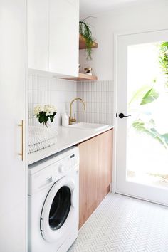 a washer and dryer in a small room with white tile flooring on the walls