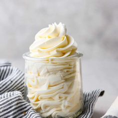 a glass jar filled with whipped cream on top of a striped cloth next to a knife