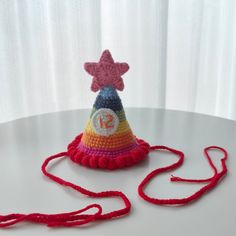 a crocheted hat with a star on top and a red string around it