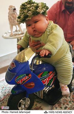 a baby sitting on top of a toy motorcycle