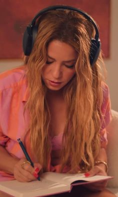 a woman with headphones on writing in a notebook