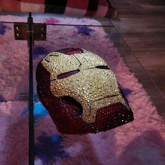 the iron man mask is on display in front of a glass table with pink carpet