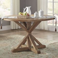 a wooden table topped with fruit and two white vases on top of a rug