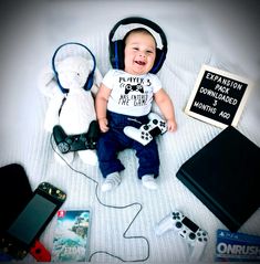 a baby sitting on top of a bed next to some electronic devices and a sign