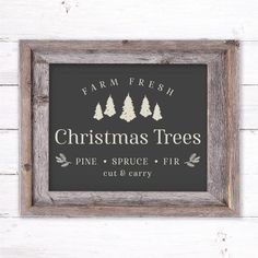 a wooden frame with the words christmas trees painted on it and pine trees in front