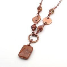 "This necklace measures 21.75\" long (55.5cm) and features a red fossilized coral bead.  I have paired it with antiqued copper tone chain.  I've accented it with birdseye rhyolite beads. The toggle clasp and spacer beads are made from copper-plated leadfree pewter.  The textured ring, headpin, chain, and links are made of copper plated base metal.   The jump rings are made of enameled copper. The fossil coral bead measures 13/16\" long (20mm).  The birdseye rhyolite beads measure 5/16\" in diame Adjustable Copper Necklace With Natural Stones, Brown Jasper Gemstone Bead Necklaces, Brown Jasper Gemstone Bead Necklace, Brown Jasper Necklace With Gemstone Beads, Brown Jasper Gemstone Beaded Necklace, Brown Jasper Necklace With Natural Stones, Handmade Rust Copper Necklaces, Handmade Rust-colored Copper Necklaces, Brown Wire Wrapped Copper Necklace