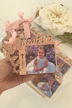 a person holding up a card with an image of a baby on it and flowers in the background