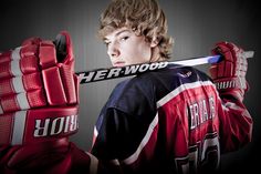 a young man holding a hockey stick in front of his face with the words herwood written on it