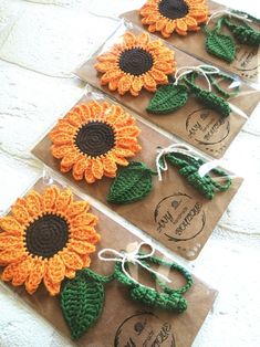 crocheted sunflowers are on brown paper with green and orange leaves attached to them