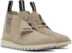 Ankle-high suede desert boots in taupe. · Embroidered detailing at vamp · Logo tags at lace-up closure · Logo-woven pull-loop at tongue and heel collar · Logo and text printed at sides · Elasticized gussets · Padded leather footbed · Buffed sheepskin and suede lining · Treaded Vibram® EVA foam rubber sole · Contrast stitching in gray Part of the Clarks Originals x Neighborhood collaboration. Supplier color: Beige Beige Suede High-top Desert Boots, Beige High-top Suede Desert Boots, Beige Suede Lace-up Desert Boots, Clarks Originals, Desert Boots, Eva Foam, Contrast Stitch, Rubber Sole, The Neighbourhood