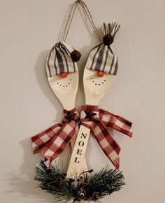 two wooden spoons decorated with plaid bows hang on a wall