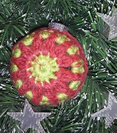 a crocheted ornament is hanging on a christmas tree with silver stars