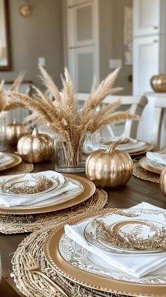 the table is set with gold and white plates, silverware, and pumpkins