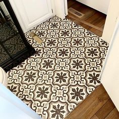 the door mat is on the floor in front of an open door with a black and white pattern