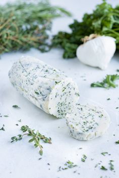 garlic, herbs and cheese on a white surface