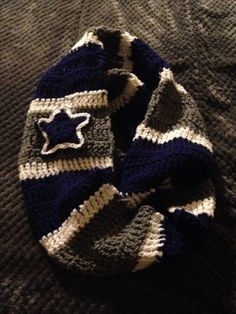 a knitted hat with a star on it sitting on top of a bed next to a blanket