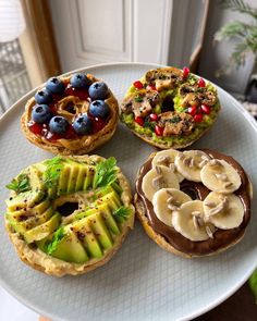 four different types of pastries on a white plate with fruit and chocolate toppings