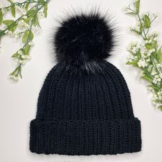 a black knitted hat with a fur pom - pom on the top