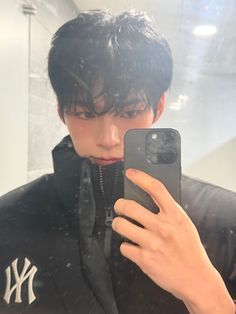 a young man taking a selfie in front of a mirror with his cell phone