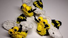 four crocheted yellow and black birds with big eyes sitting on a white surface