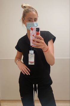 a woman wearing a face mask and holding up her cell phone to take a selfie