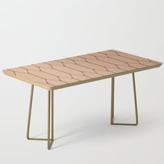 a pink and gold coffee table with geometric lines on the top, against a white background