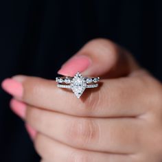 a woman's hand holding an engagement ring with two diamonds on top of it