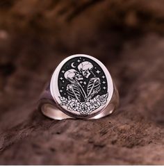 Dive into the enchanting world of romance and mystery with our Skull Lovers Ring, a captivating blend of delicate florals and edgy symbolism. Whether you're searching for the perfect gift for her or him, this Dainty Floral Skull Lovers Signet Ring is sure to delight with its unique charm. For the man who appreciates subtle yet striking accessories, our Skeleton Lovers Pinky Ring is an ideal choice. Crafted with meticulous attention to detail, this ring is a timeless expression of style and indiv Adjustable Gothic Skull Ring As A Gift, Gothic Rings For Valentine's Day Gift, Valentine's Day Gothic Rings As Gift, Symbolic Rings As Halloween Gifts, Skull Shaped Ring As Halloween Gift, Symbolic Rings For Halloween Gift, Sterling Silver Skull Ring Gift, Nickel-free Skull Rings For Gift, Gothic Engraved Rings For Gift