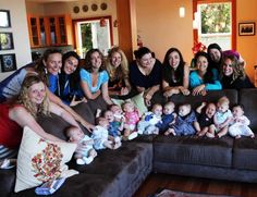 a large group of women and babys posing for a photo in the living room