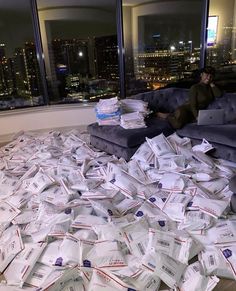 a pile of papers sitting on top of a floor next to a couch in front of a window