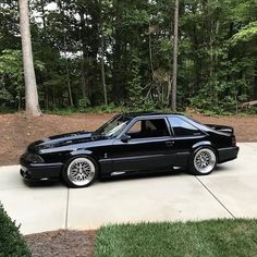 a black car parked in front of some trees