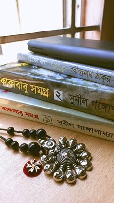 a stack of books sitting on top of a table next to a pair of earrings