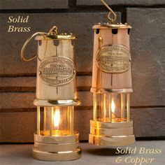 two brass colored lamps sitting next to each other on top of a stone wall with the words solid brass and copper