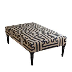 a black and white ottoman sitting on top of a wooden leg rest with an intricate design