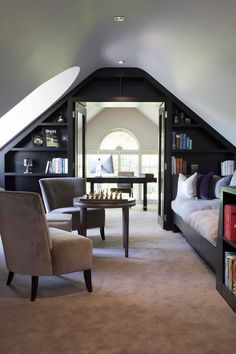 an attic bedroom with two chairs and a desk in the corner, along with bookshelves