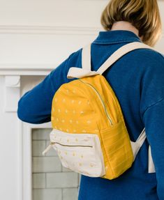 woman in blue shirt wears the mustard yellow and white small backpack with delicate hand embroidered daisies Daisy Backpack, Playful Aesthetic, Functional Backpack, Waffle Blanket, Fair Trade Clothing, Organic Bedding, Stoneware Dinnerware Sets, Backpack Bag, Mini Backpack