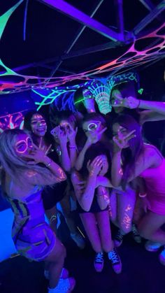 a group of young women standing next to each other in front of neon colored lights