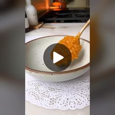 a bowl filled with food on top of a white tablecloth next to a wooden spoon