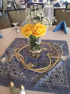 a vase with yellow roses and baby's breath sits on a blue table cloth