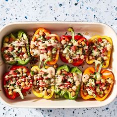 several peppers stuffed with various toppings in a white casserole dish