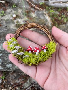 a hand holding a small wreath with mushrooms on it