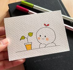 a hand holding up a card with a drawing of a baby in a pot on it