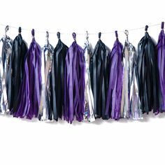 purple and black tassels hanging from clothes pins on a line with ribbons attached to them