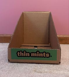 an open cardboard box with the word thin mints on it sitting in front of a pink wall