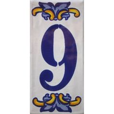 a blue and yellow number nine hanging from the side of a white wall with an ornate design on it