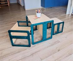 three children's wooden tables and chairs with colored pencils on them in a room