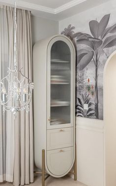 a white cabinet sitting in the corner of a room next to a chandelier