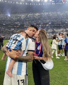 a man and woman kissing each other at a soccer game