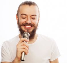 a man with a beard holding a microphone in his hand and smiling at the camera